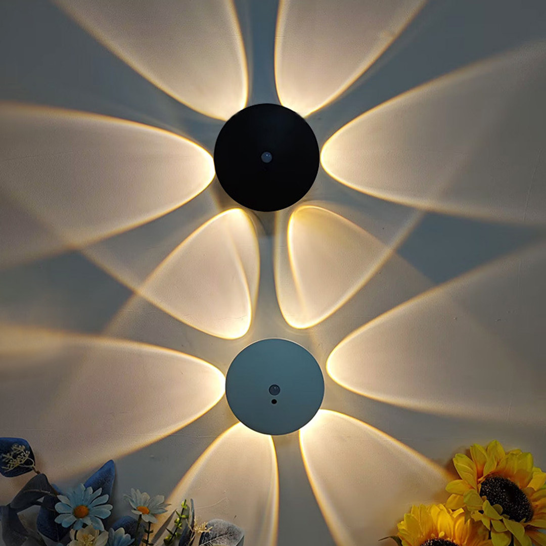 En svart og en hvit lampe på samme vegg med hvert sitt blomstermønster av lys