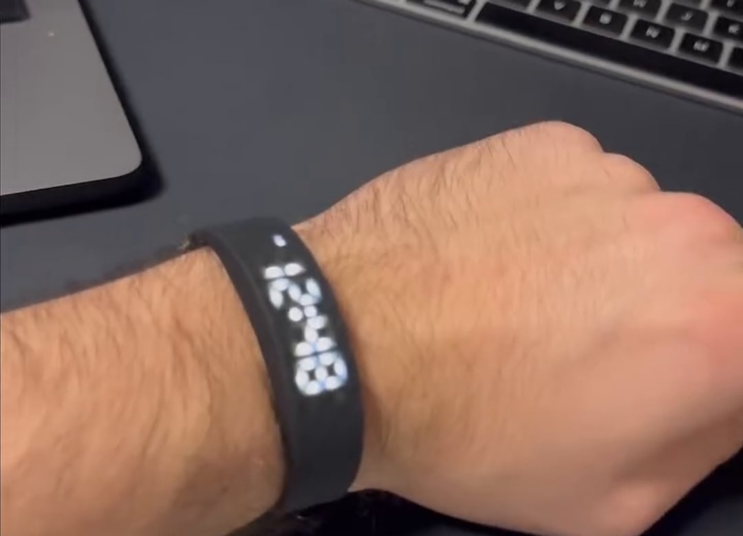 Stillvekk-armbåndet på håndleddet ved skrivebordet, skjermen viser klokkeslettet